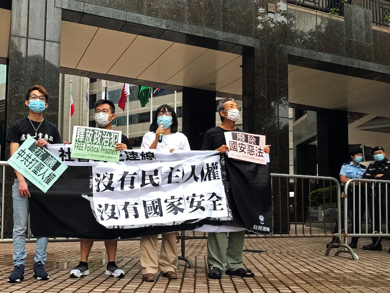 Chow Hang-tung, center, and other pro-democracy activists hold a banner and placards next to police officers during a demonstration against the National Security Education Day in Hong Kong,  April 15, 2021