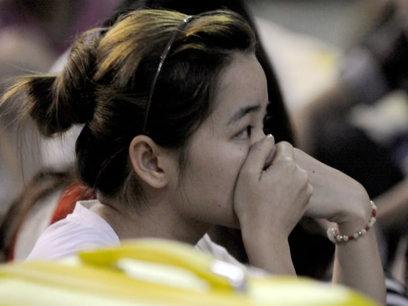 A group of Taiwanese, and mainland Chinese nationals rounded up by police on suspicion of involvement in a telephone scam, wait to be investigated by authorities at a police stadium in the town of Canlubang, Laguna province, south of Manila, Aug. 23, 2012. Credit: AFP