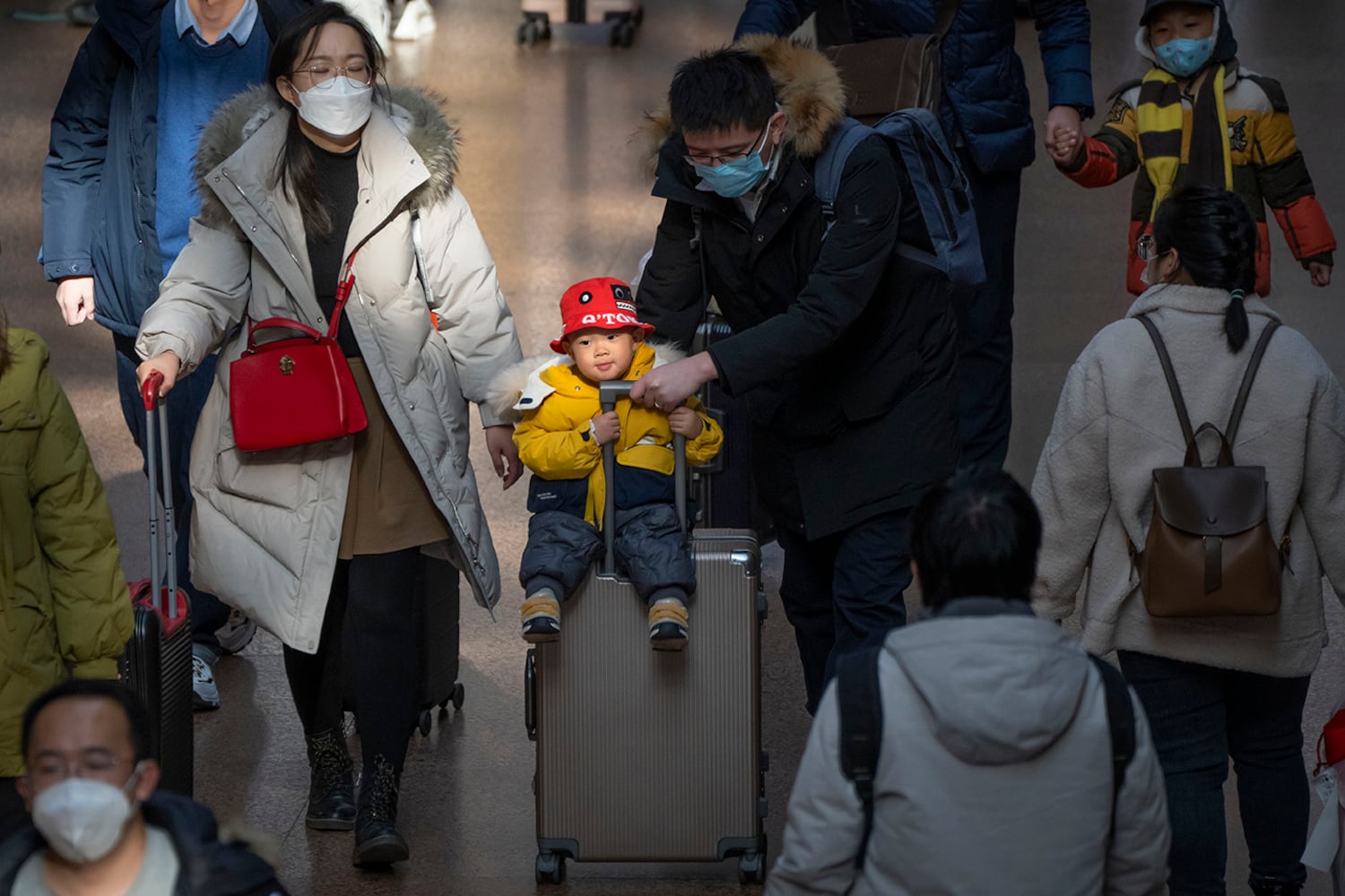 Ein Mann schiebt ein Kind, das auf einem Koffer fährt, am Pekinger Westbahnhof in Peking, 18. Januar 2023.