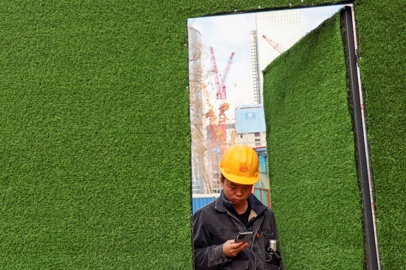 A worker checks his mobile phone as he leaves a construction site in Beijing, China January 16, 2024. (Florence Lo/Reuters)