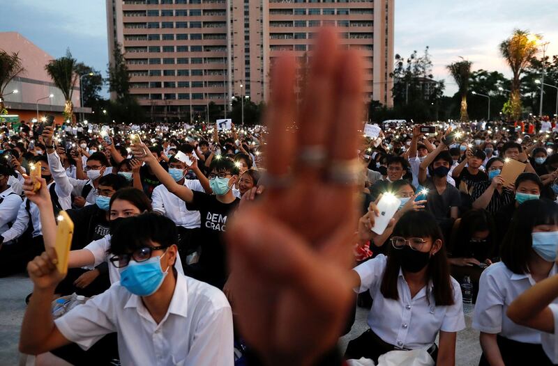 2020 年 8 月 19 日，在泰国曼谷郊区的 King Mongkut 理工学院，举行的抗议活动中，支持民主的学生举起三指象征抵抗的敬礼，并手持手电筒。（路透社图片）