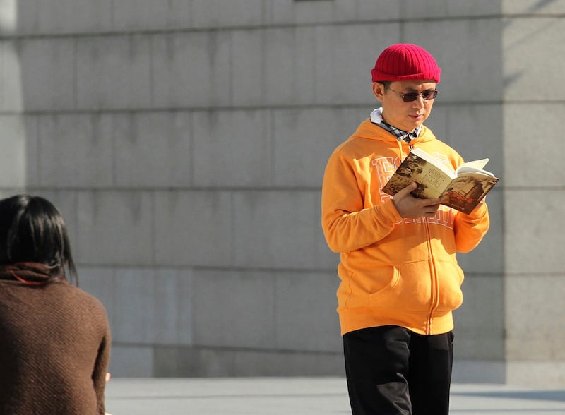 In this Dec. 2013, photo, Xiao Jianhua, a Chinese-born Canadian billionaire, reads a book outside the International Finance Centre in Hong Kong. Next Magazine via AP