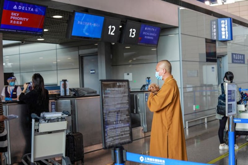 Buddhist monk Zhi Xiang carries a rescued dog before sending him to the United States, at Pudong International Airport in Shanghai, China, May 26, 2021. (Jessica Yang/AFP)