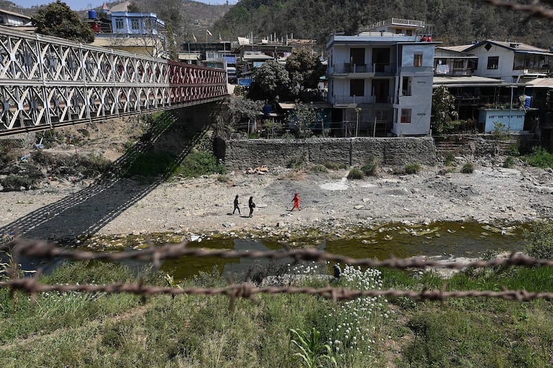 In this March 15, 2021 photo, houses in Myanmar are seen through barbed wires along the banks of the Tiau River, a natural border between India and Myanmar in India's northeastern state of Mizoram. Credit: Sajjad Hussain/AFP