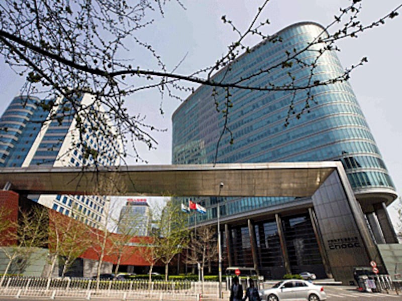 Pedestrians walk past the headquarters of China National Offshore Oil Corporation (CNOOC)in Beijing, April 5, 2015. 