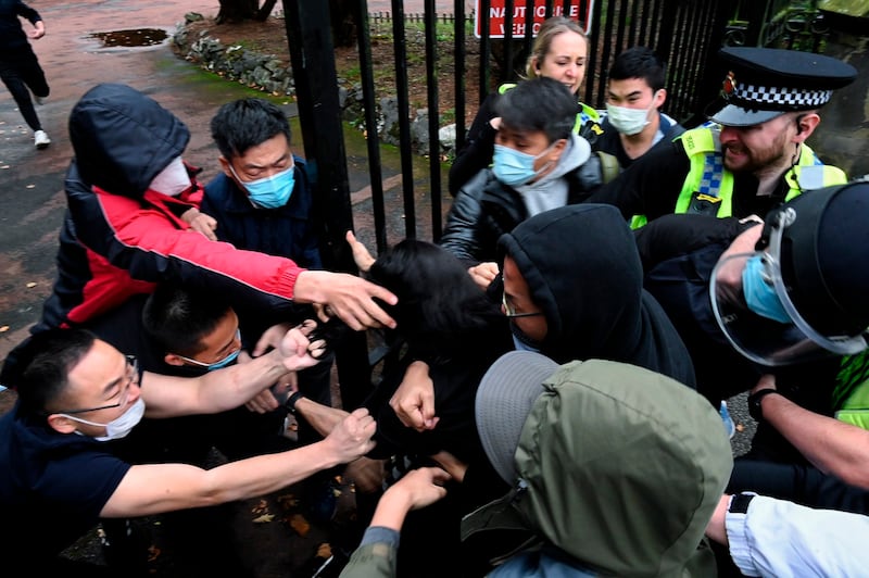 Bob Chan scuffles with people trying to drag him through the gates of the Chinese consulate grounds in Manchester, England, Oct. 16, 2022. Credit: Matthew Leung/The Chaser News via AP