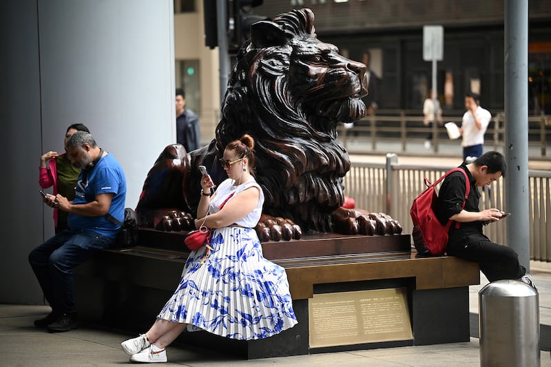 People sit outside the headquarters of HSBC in Hong Kong on Feb. 21, 2024.