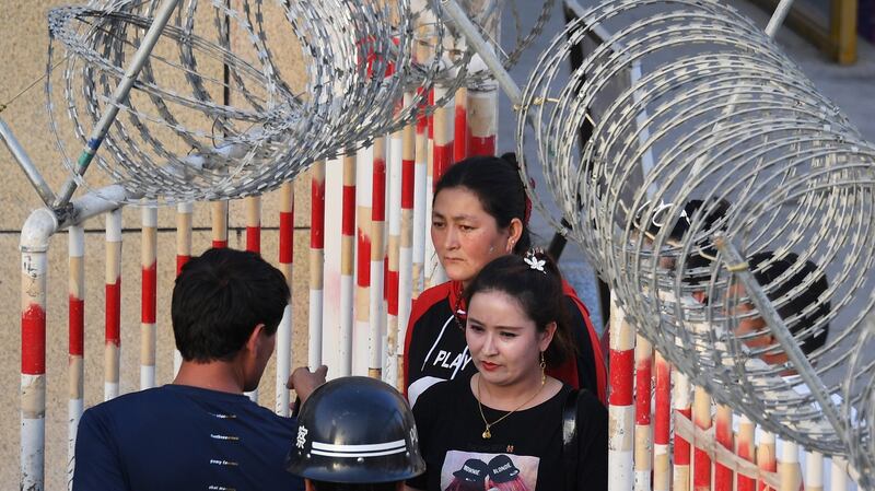 A Uyghur woman (C) walks through a security checkpoint to enter a bazaar in Hotan, in China's Xinjiang Uyghur Autonomous Region (XUAR), May 31, 2019. AFP