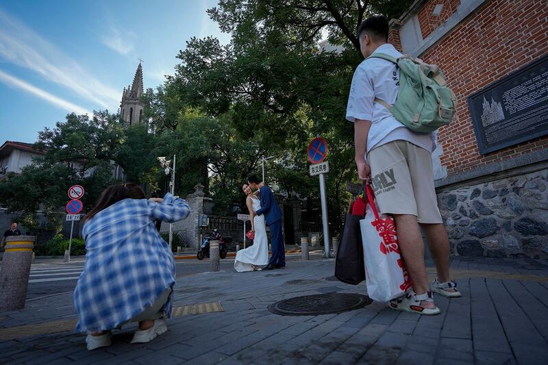 2023年9月1日，一对新婚夫妇拿着结婚证在东交民巷天主堂附近拍摄结婚照。（美联社）