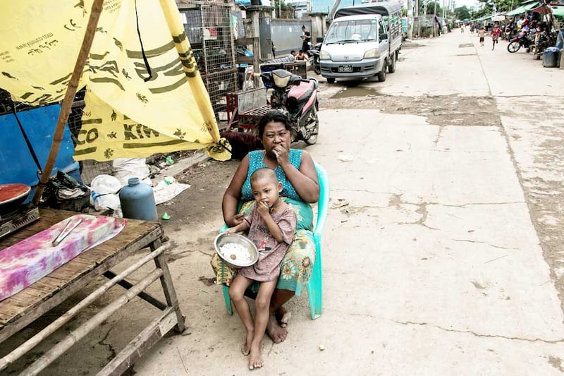 A mother and child eat in front of their home on the outskirts of Yangon. (AFP)