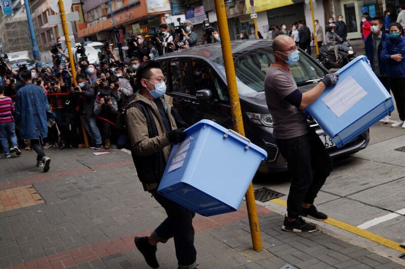 A Hong Kong national security police officer (L) and a worker carry boxes of evidence from the offices of Stand News in Hong Kong after police raided the office of the local media outlet and arrested six current and former staff, Dec. 29, 2021. Credit: AFP