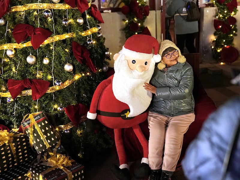 A woman poses for pictures with a Santa Claus decoration at Xishiku Church on Christmas Eve in Beijing, China ,Dec. 24, 2024.