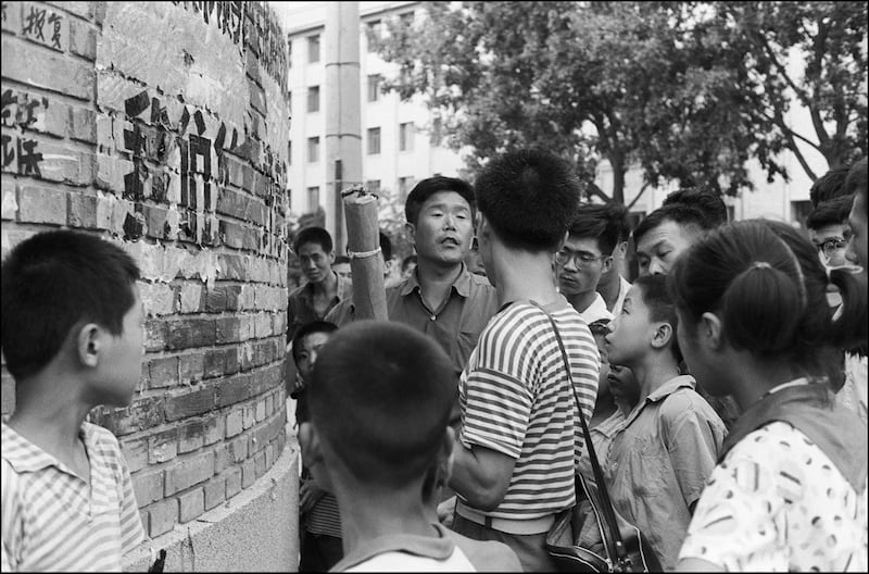 An angry Chinese (striped T-shirt) is heckled in Beijing by a plain-clothes militiaman (facing camera) while trying to roll out and paste his hand-written placard or dazibao on the "dazibao wall" in front of the Municipal Revolutionary Committee of Beijing, July 23, 1974. Credit: AFP