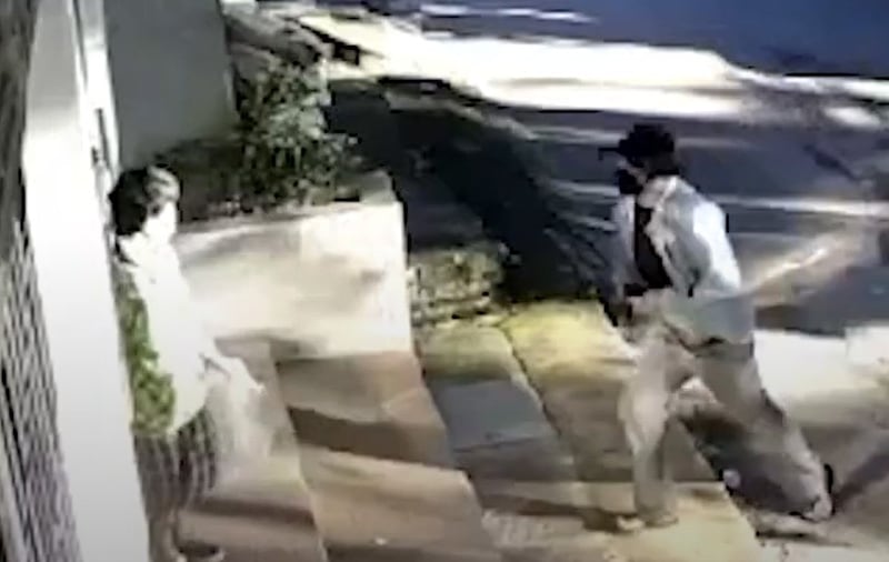 A man confronts a woman as she leaves a building before pushing her back inside.