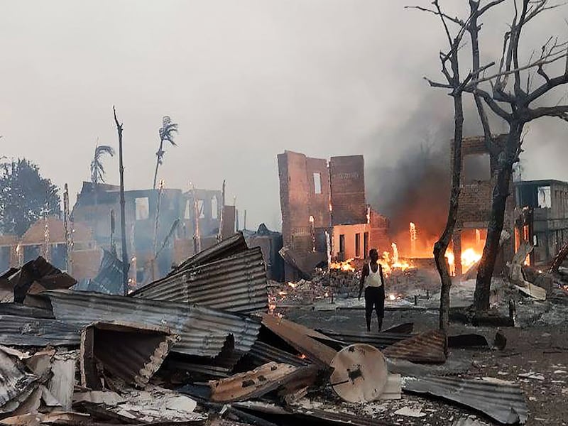 A man standing near a burning house at the site of a suspected air strike carried out by Myanmar's military at Kyauk Ni Maw village in Ramree island in western Rakhine State, Jan. 9, 2025 .