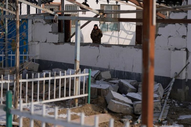 Nurahun Osman walks near a collapsed wall damaged by the earthquake in Yamansu township, Aksu prefecture, in northwestern China's Xinjiang region, Jan. 24, 2024. (Ng Han Guan/AP)