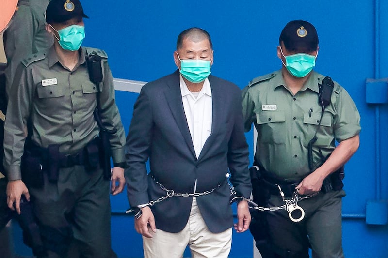 Jimmy Lai, center, who founded the Apple Daily tabloid, is escorted by Correctional Services officers to get on a prison van before appearing in a court, in Hong Kong, Dec. 12, 2020. (Kin Cheung/AP)