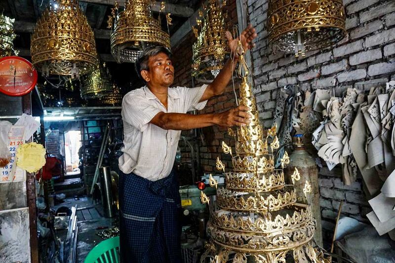 A worker puts the final touches on a small holy umbrella for a pagoda's finial, which can take from one to two weeks to make, depending on the size. (Myo Min Soe/RFA)