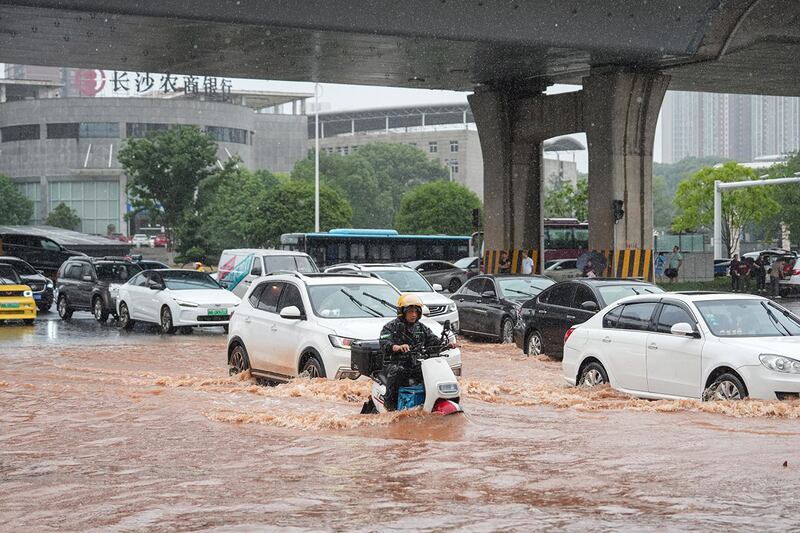 2024年6月24日，汽车驶过被洪水淹没的湖南长沙街道。（法新社）