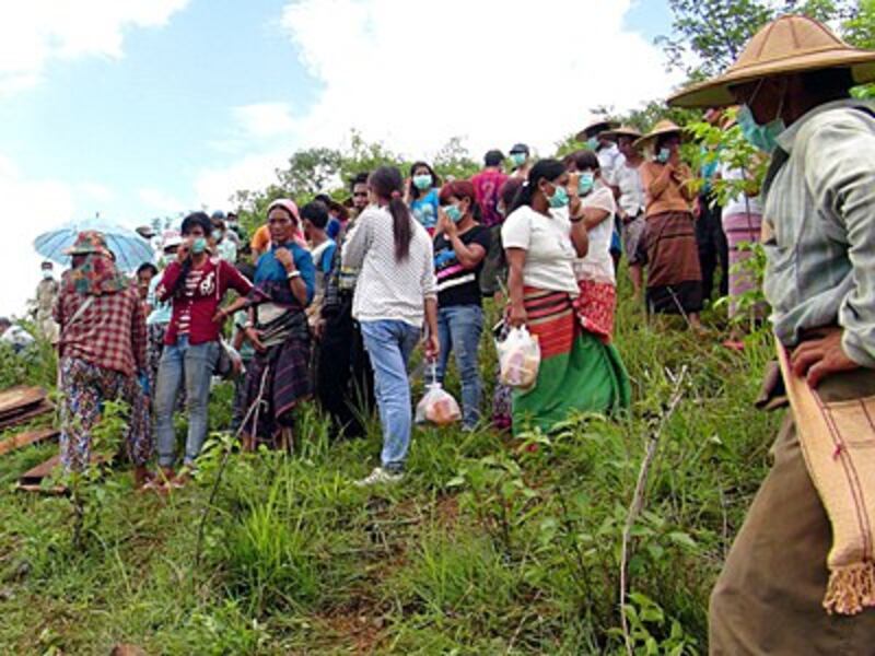 Villagers watch while corpses are removed from shallow graves in Long Mon village of Mong Yaw subtownship in Myanmar's northern Shan state, June 30, 2016.