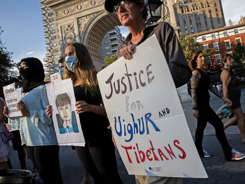 Protesters hold photos of Ekpar Asat during a rally in support of the Uyghurs, in New York City,  August 12, 2021.