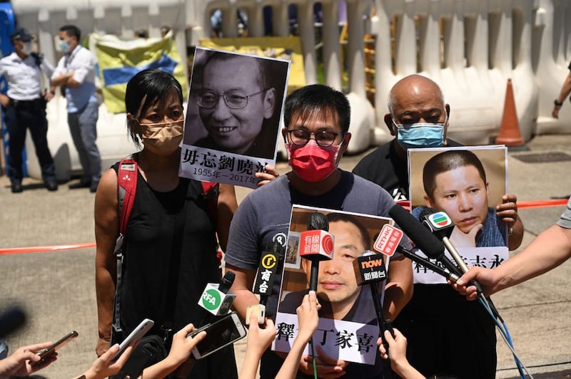 Members of the pro-democracy group League of Social Democrats gather outside the Chinese Liaison Office in Hong Kong and hold up portraits of political prisoners, including one of Chinese Nobel Peace laureate Liu Xiaobo (pictured top L) on the fourth anniversary of his death, July 13, 2021. Credit: AFP