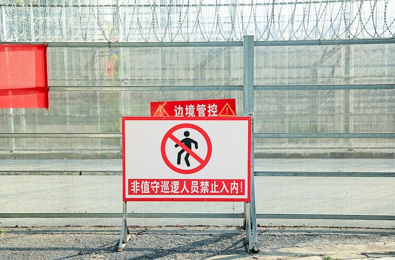 A part of a border wall between China and Myanmar with barbed wire and warning signs, in Ruili, west Yunnan province, Jan. 14, 2023. (Noel Celis/AFP)