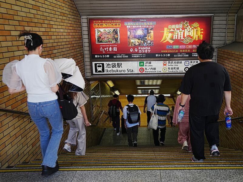 Commuters walks past advertisements of Chinese restaurant and karaoke, which are popular among Chinese living in Japan, at Ikebukuro station, Sept. 4, 2024, in Tokyo.