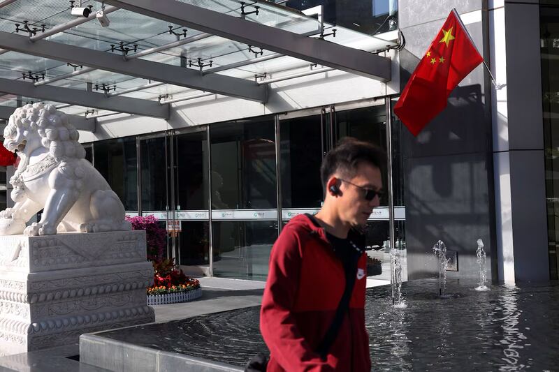 A man walks past a Chinese flag decorating an office building on the Financial Street in Beijing, China Oct. 8, 2024.