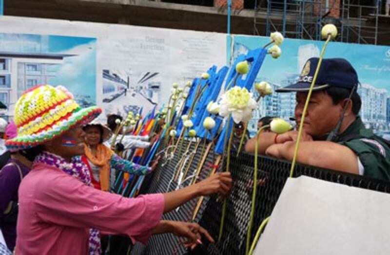 A supporter places a flower in front of security personnel outside the court in Phnom Penh, May 6, 2014. Credit: RFA