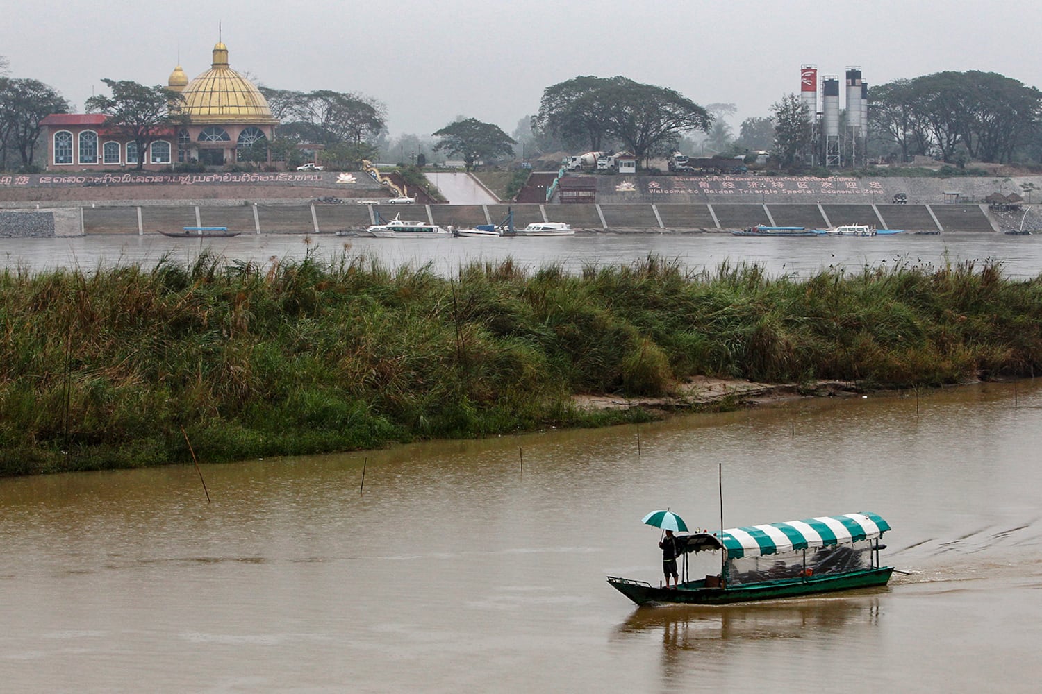 A man stands on a small boat travelling along the Mekong river in front of the Kings Roman casino in the Golden Triangle Special Economic Zone in Laos, Jan. 14, 2012.