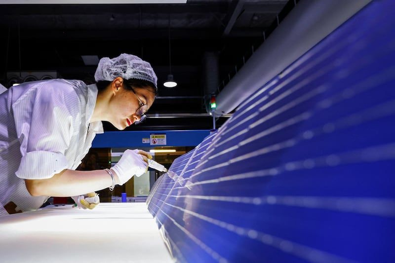 An employee works on solar photovoltaic modules for export at a factory in Sihong, in eastern China's Jiangsu province.