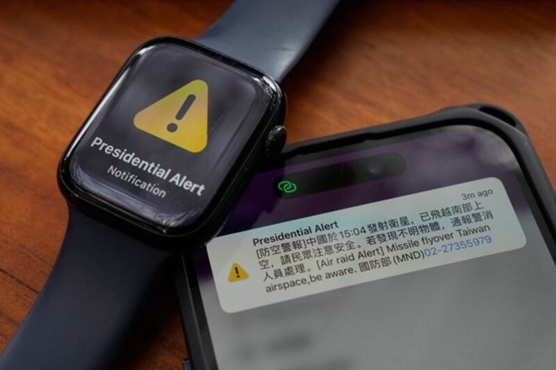 A phone and watch display Taiwan's air raid alert on Jan. 9, 2024. The Ministry of National Defense text alert about a Chinese satellite launch caused alarm because the English part of the text referred to the rocket as a 'missile.' (Ng Han Guan/AP)