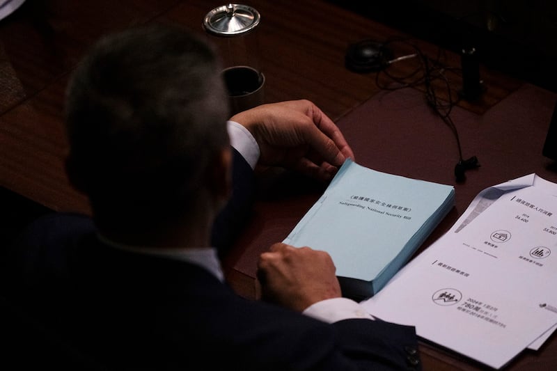 A lawmaker holds a copy of the Safeguarding National Security Bill during the second reading of the Basic Law Article 23 legislation at the Legislative Council in Hong Kong, March 19, 2024. (Louise Delmotte/AP)