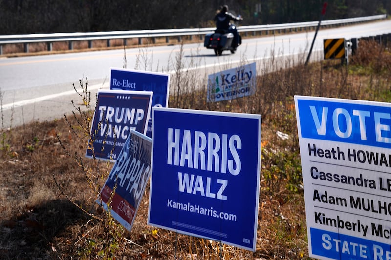 A motorcyclist rolls past campaign signs on Oct. 31, 2024, in Barrington, New Hampshire.