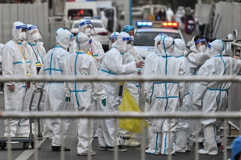 Officials and workers, wearing protective gear, work in an area where barriers are being placed to close off streets around a locked down neighborhood after the detection of new cases of Covid-19 in Shanghai, March 15, 2022. Credit: AFP