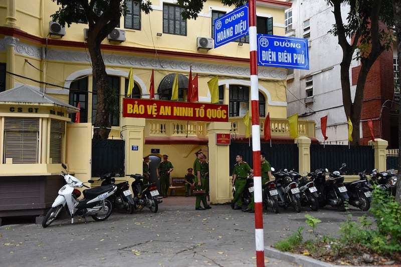 Officers wait around outside a police station in central Hanoi, Aug. 17, 2024.