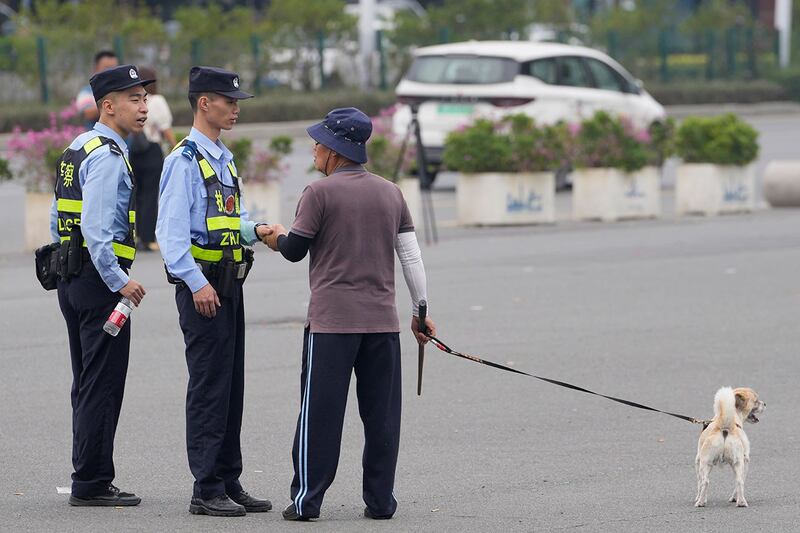 珠海越野车冲撞事件造成至少78人死伤。2024年11月13日，珠海市体育中心外，警察与遛狗男子交谈。（美联社）