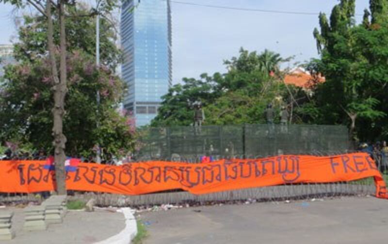 A protest banner hangs on a barbed wire barricade in front of Freedom Park in Phnom Penh, July 15, 2014. Credit: RFA