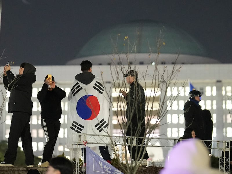 A man wearing a national flag stands on the wall of the National Assembly in Seoul, Dec. 4, 2024.