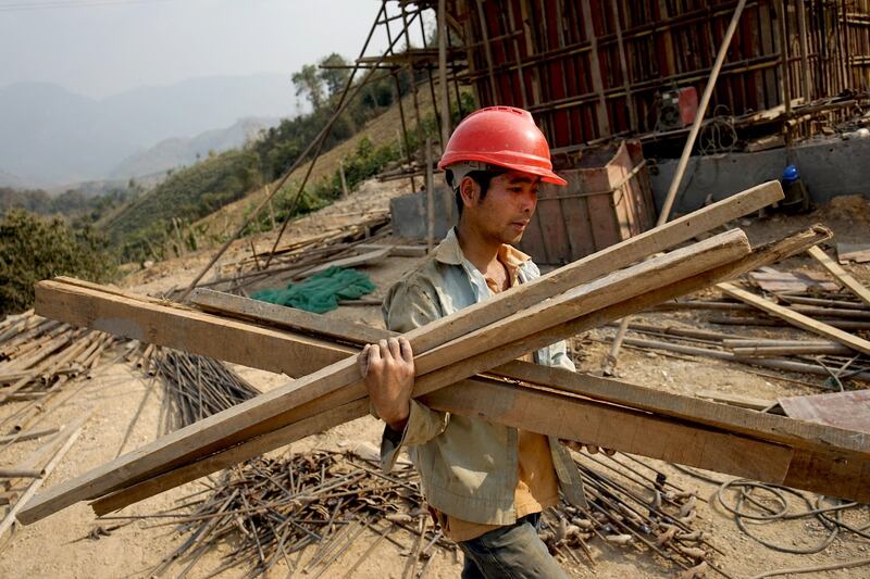 A Chinese worker carries materials for the first rail line linking China to Laos, a key part of Beijing's 'Belt and Road' project across the Mekong River, in Luang Prabang, Feb. 8, 2020. Credit: AFP