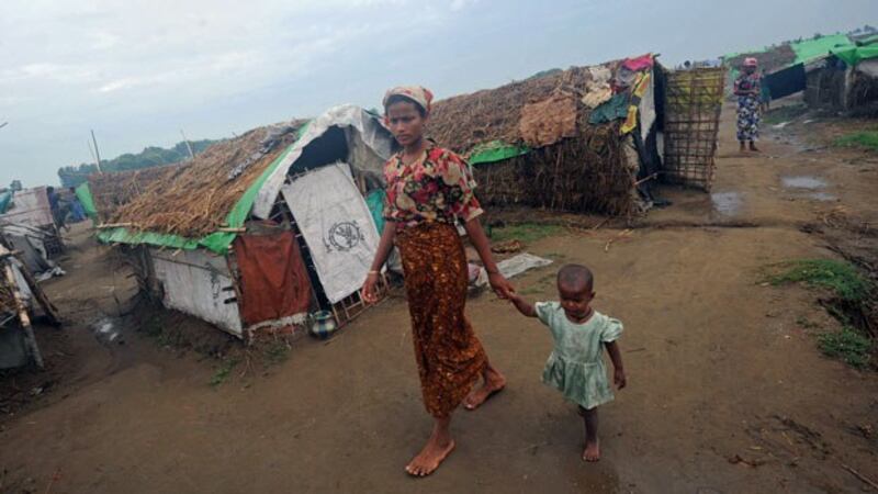 A Rohingya woman and her child walk in front of tents at the Mansi IDP camp on the outskirts of Sittwe in western Myanmar's Rakhine state, May 15, 2013.