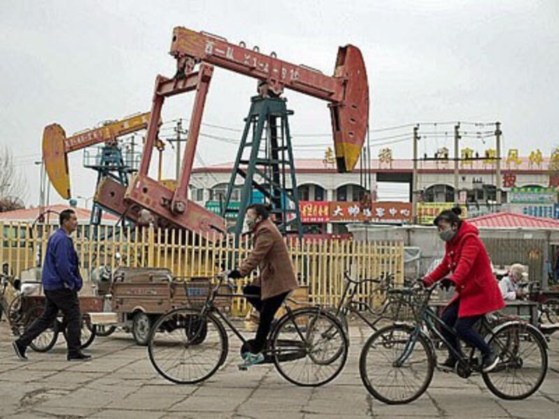 Chinese residents riding bicycles by oil derricks in Daqing, China's largest oilfield in the country's northeastern Heilongjiang province, May 2, 2016. 