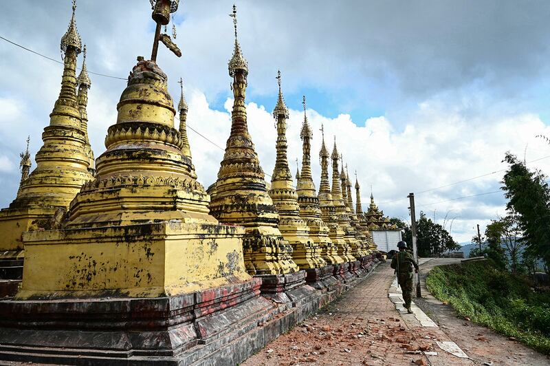 A member of the Ta'ang National Liberation Army walks past damaged pagodas amid clashes with Myanmar’s military in Namhsan township in Myanmar's northern Shan State, Dec. 12, 2023.