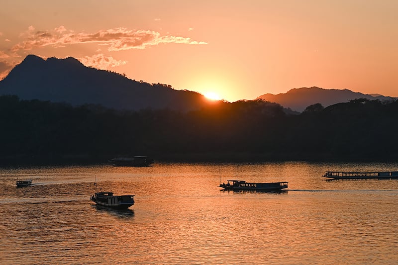 Tourists watch the sunset as they travel in boats along the Mekong river in Luang Prabang, Laos, on Jan. 31, 2024.