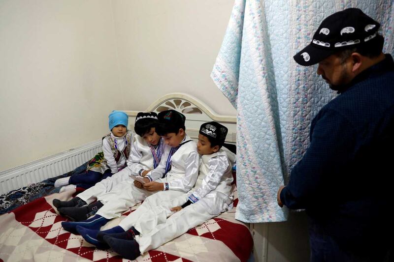 Qurbanjan Nourmuhammed looks on as his children play a game on a mobile phone at their home in Istanbul, Turkey, Dec. 12, 2018. Credit: Reuters