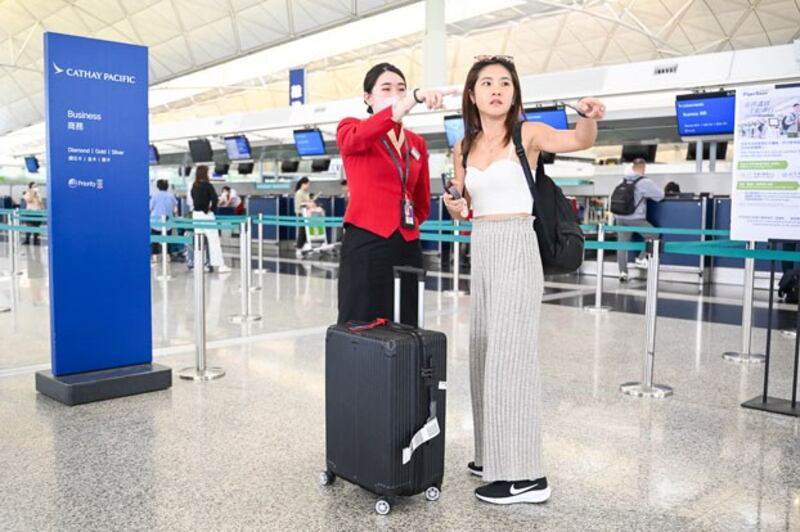 A Cathay Pacific employee talks to a passenger at the international airport in Hong Kong, Sept. 4, 2024. (Peter Parks/AFP)