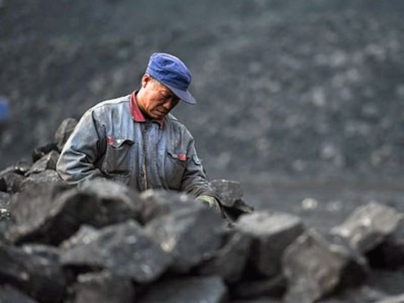 A Chinese worker sorts coal on a conveyor belt near a coal mine in Datong, northern China's Shanxi province, Nov. 20, 2015.