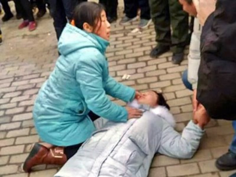 The daughter of Chinese rights lawyer Shu Xiangxin is beaten unconscious outside the Licheng District People's Court in Jinan, Shandong province, Jan. 8, 2016. 