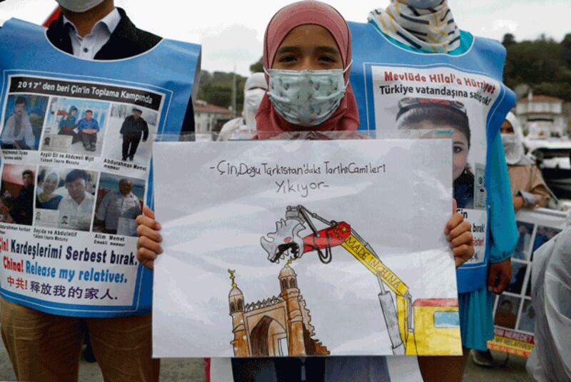 A woman holds a placard reading 'China is destroying historical mosques in East Turkistan,' using Uyghurs' preferred name for northwestern China's Xinjiang region, during a protest by members of the Uyghur community living in Turkey, outside the Chinese consulate in Istanbul, June 2, 2021. Credit: Associated Press